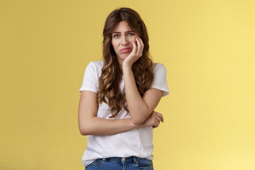 Upset distressed cute disappointed pretty girl feeling lonely regretting missed opportunity sighing sorrow sadness look camera apathetic indifferent lean face palm frowning jealous yellow background.