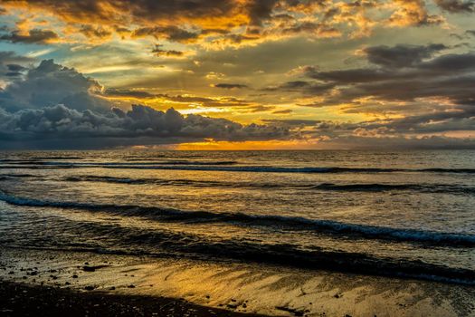 Evening view of the Pacific Coast of Tarcoles in Carara lit by the setting sun and glittering waves . Idyllic sunset landscape. Tarcoles, Costa Rica. Pura Vida concept, travel to exotic tropical country.