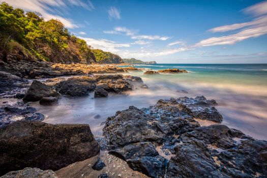 Long exposure, pacific ocean waves on rock in Playa Ocotal, El Coco Costa Rica. Famous snorkel beach. Picturesque paradise tropical landscape of Costa Rica beach. Pura Vida concept, travel to exotic tropical country.