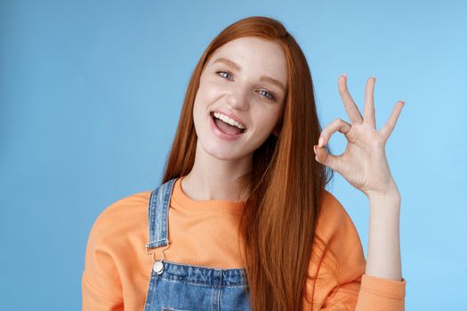 Studio shot carefree happy attractive european redhead girl show okay ok sign smiling white teeth approval confirmation recommend good product agree terms give positive feedback, think idea perfect.