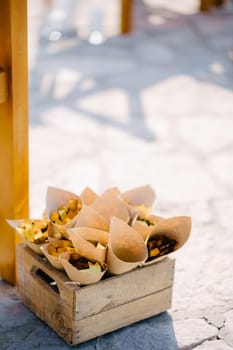Box with flower petals in rolled sheets of paper stands on a stone floor. High quality photo