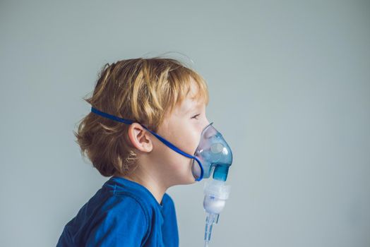 Boy making inhalation with a nebulizer at home.