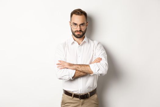 Angry manager looking disappointed, cross arms on chest and frowning displeased, standing over white background. Copy space