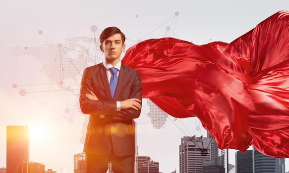 Young confident businessman wearing red cape against modern city background