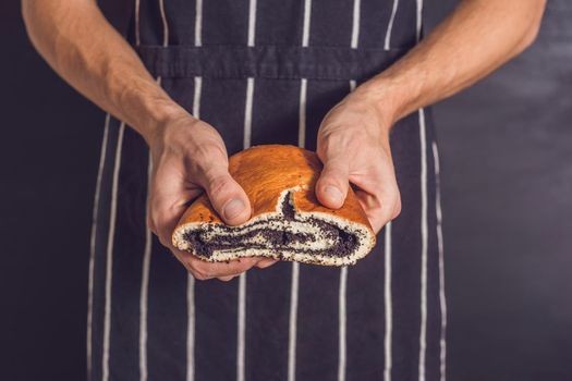 Roll with poppy seeds in the hands of a baker.