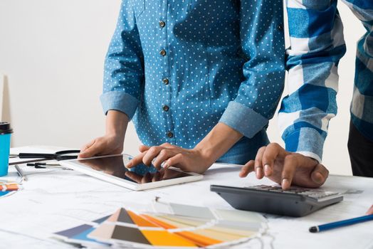 Designers working with color swatches and tablet computer at desk. Interior design, architectural decoration and renovation. Brainstorm, teamwork and creativity. Decorator workplace in design agency