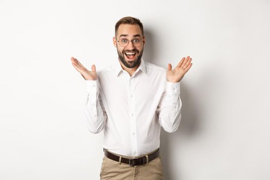 Surprised happy male entrepreneur clap hands and smiling, looking amazed at camera, standing over white background.