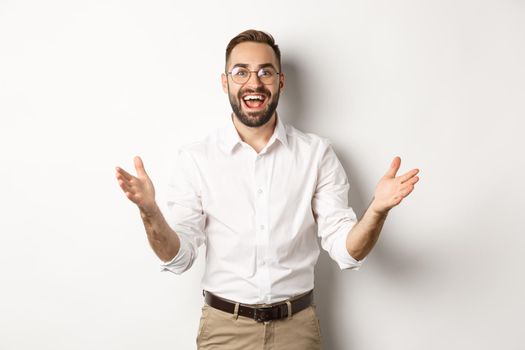 Surprised and happy businessman welcome you, looking excited and smiling, standing against white background.