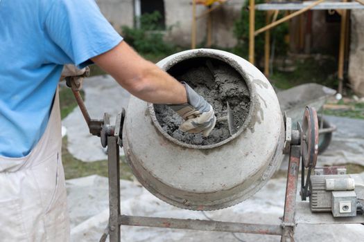 builder laborer man working with front of concrete cement mixer at construction site