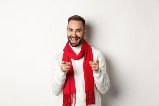 Winter holidays and shopping concept. Bearded man pointing fingers at you to praise or say congrats, wishing happy christmas, standing over white background.
