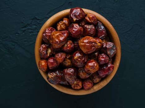 Dried fruits of Capsicum frutescens, used as hot spice and for tabasco sauce. Whole small dry red hot pepper on bowl in black stone background. Spices and seasonings for cooking. Top view. Soft focus