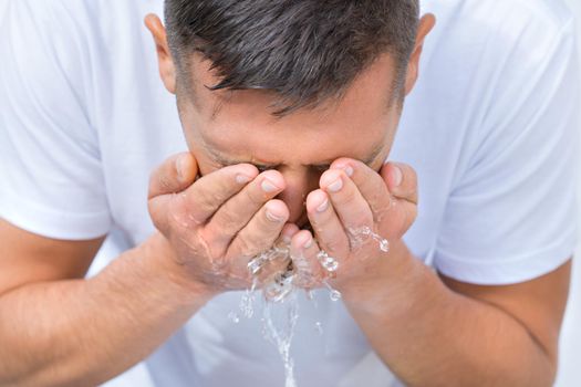 Portrait of young man washing face with a splash of water in the morning. High quality photo