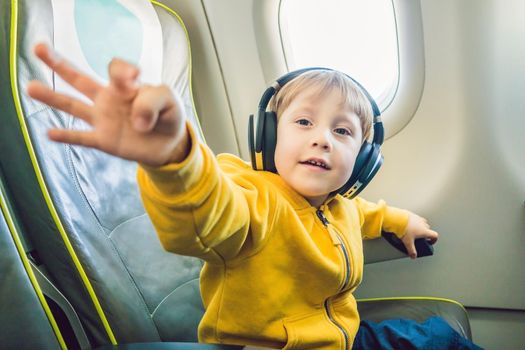 Boy with headphones watching and listening to in flight entertainment on board airplane.