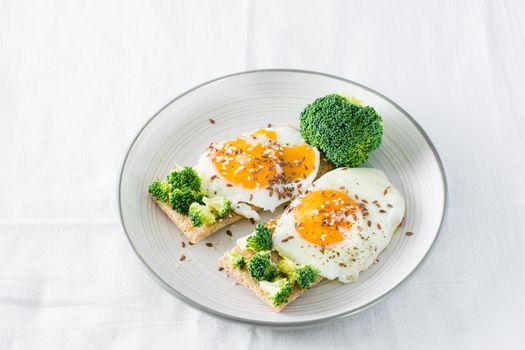 Bruschetta with scrambled eggs and broccoli on a grain crispbread on a plate on the table