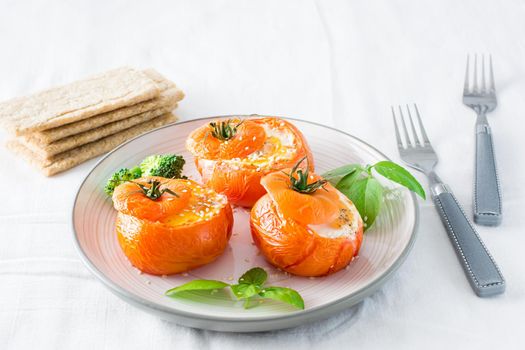 Baked tomatoes with egg and basil leaves on the table. Diet lunch