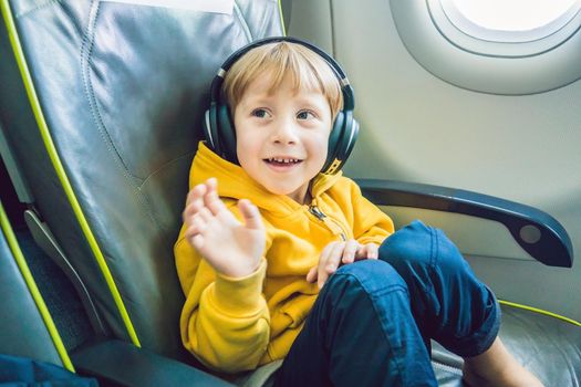 Boy with headphones watching and listening to in flight entertainment on board airplane.