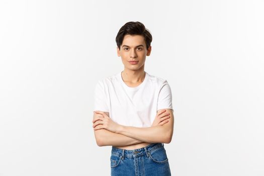 Image of sassy gay man in crop top smiling, looking confident, cross arms on chest and standing over white background.