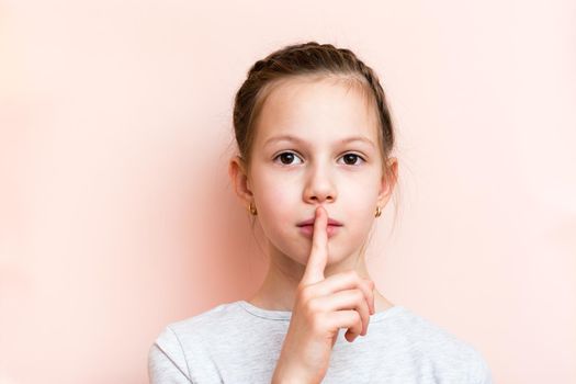 Surprised girl holds her finger in front of her lips. Call for silence