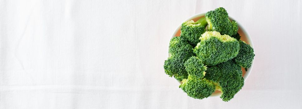 Fresh broccoli in a bowl on a table on a cloth. Diet healthy food. Top view. Copy space. Web banner