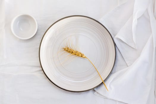 An ear of grain on an empty plate on the table. Top view