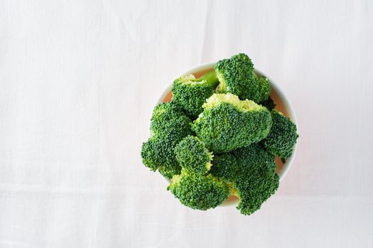 Fresh broccoli in a bowl on a table on a cloth. Diet healthy food. Top view. Copy space