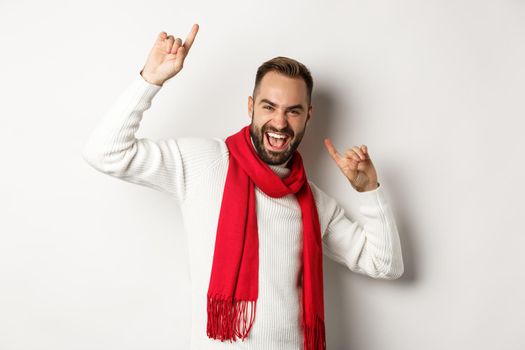 Happy bearded man celebrating new year party, dancing and pointing fingers, standing over white background.