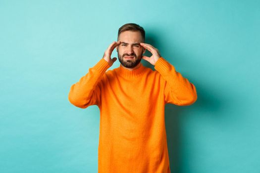 Phoro of caucasian man touching head, feeling sick, have headache or migraine, hangover after party, standing over light blue background.