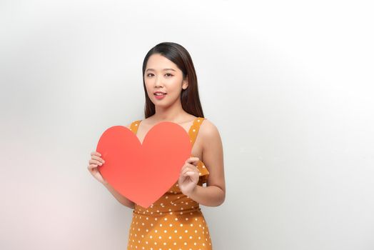 The happy woman holding a heart symbol on the white background