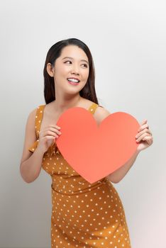 Portrait of attractive asian smiling woman holding red heart on white background