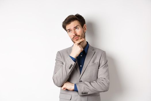 Thoughtful businessman in grey suit look at upper left corner logo, thinking or making choice, pondering plan, standing against white background.