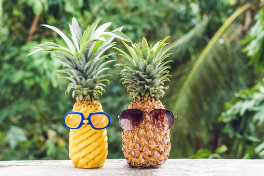 Couple of funny attractive pineapples in glasses and glasses for swimming on a tropical terrace. tropical island.