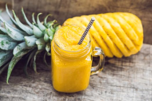 Pineapple smoothie with fresh pineapple on wooden table.