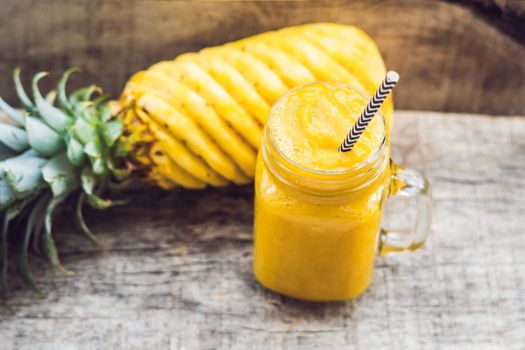 Pineapple smoothie with fresh pineapple on wooden table.