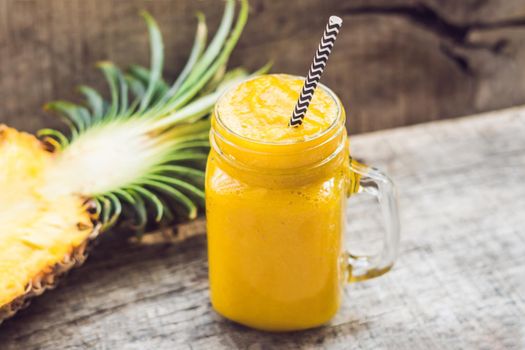 Pineapple smoothie with fresh pineapple on wooden table.