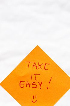 Take it easy handwriting text close up isolated on orange paper with copy space.