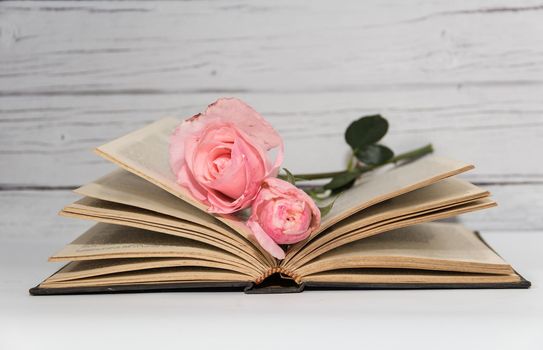 a bouquet of pink roses and books on rustic wood