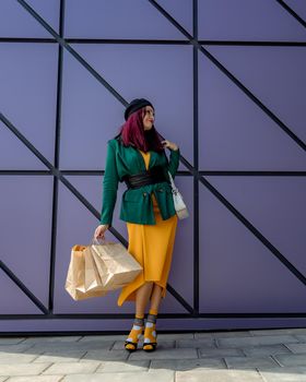 A happy shopaholic girl throws her bags near a shopping center. Have fun shopping on Black Friday. the girl in the store is happy with her purchases, throws packages. Consumer concept