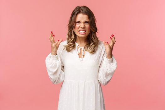 Portrait of woman losing control over emotions, feel pressured and tensed, lose temper, clench hands into fists and stare aggressive with angry, outraged expression, hate someone badly.