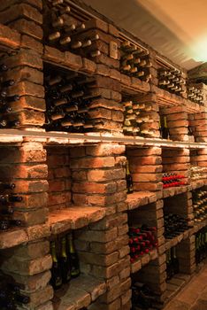 In a wine cellar, a number of false good wine are stored on a brick shelf.