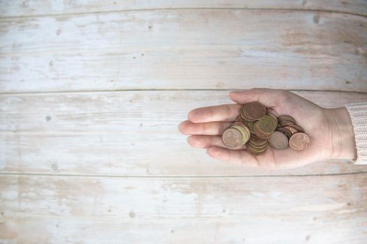 Hands holding pile of money euro coins in hand on wood background. Donation, saving, fundraising charity, family finance plan concept, financial crisis concept. Top view. copy space space for text