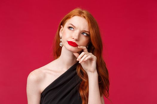 Romance, elegance, beauty and women concept. Close-up portrait of thoughful and suspicious redhead elegant woman in black evening dress having doubts, look away with serious face.