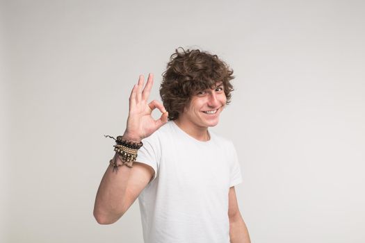 young handsome freckled man on white background showing ok sign