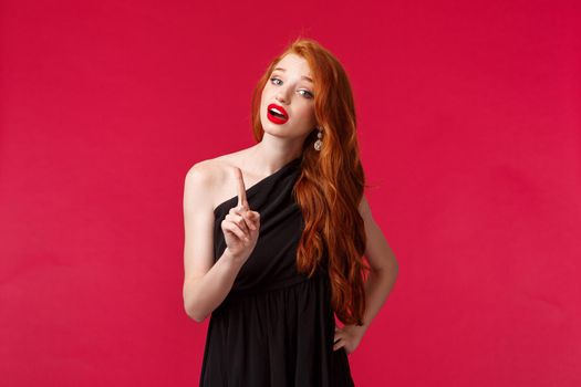 Fashion, luxury and beauty concept. Portrait of bossy good-looking young redhead woman in black dress give warning, shaking finger in caution scolding someone, give stop sign, patronising.