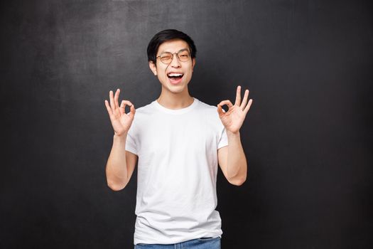 Relaxed and unbothered asian boyfriend saying to relax and calm down, all be good, show okay signs and wink as assure everything alright, rate excellent choice, agree with person, black background.