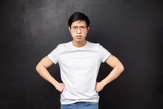 Explain yourself now. Serious-looking angry and displeased asian elder brother scolding sibling for playing late, hold hands over waist and frowning disappointed, ground child give punishment.