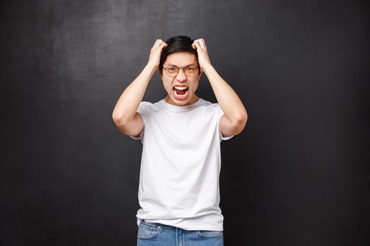 Angry and pissed-off bothered young asian guy losing temper, screaming outraged, ripping hair out of head and grimacing aggressive, feel distressed and tensed, hateful expression.