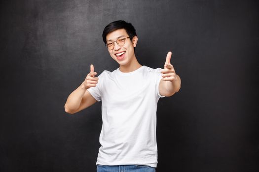 Your rock man. Cheerful handsome young asian guy attend awesome party praise nice work, pointing at camera, recruiting person join his team, smiling happy, black background.
