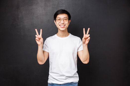 Lifestyle and people concept. Cute young asian hipster guy in white t-shirt and sunglasses make kawaii peace signs and smiling carefree, relaxing on party, enjoying chill spring day.