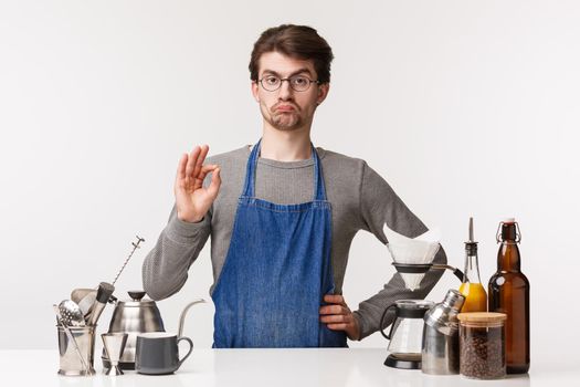 Barista, cafe worker and bartender concept. Very good, impressed and satisfied caucasian guy employee, running own business and working there, show okay sign, guarantee client will like coffee.