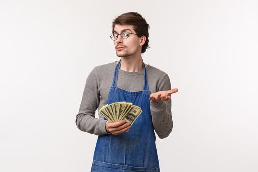 Small business, finance and career concept. Portrait of greedy caucasian male in apron pointing with hand at camera and holding cash, acting clueless dont know anything, dont tell how he got rich.